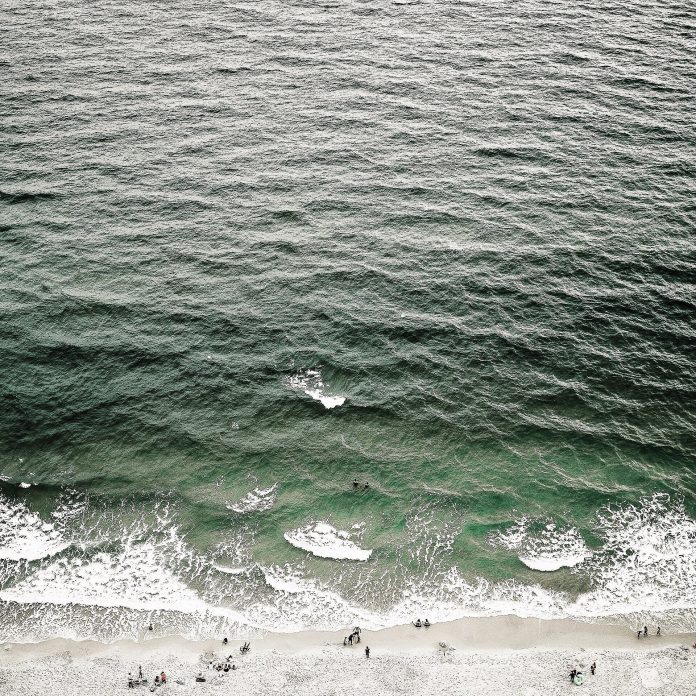 An aerial drone view of ocean waves rolling towards the shore