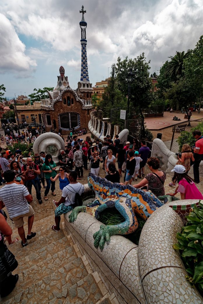 Tourists on the main stairs at Park Güell in Barcelona, around the El Drac mosaic fountain